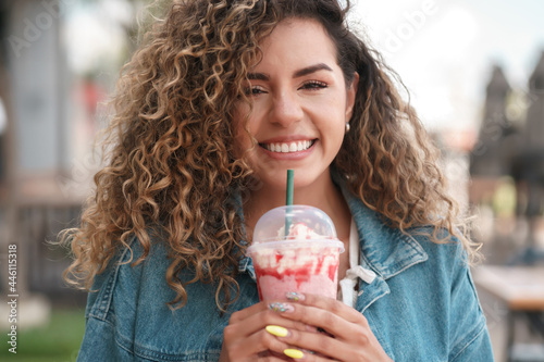Young woman drinking a cold drink beverage at a coffee shop.