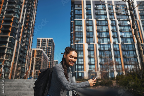 Jolly tourist with a backpack and a smartphone looking ahead