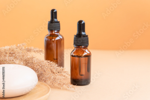 Dark glass bottles with essential oils and face soap bar on beige background. Skin care concet with copy soace. Natural cosmetics