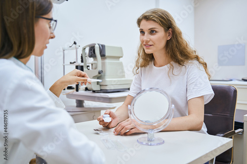 Beautiful young woman having consultation with oculist in clinic