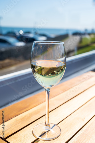 Glass of white wine served on outdoor terrase with seaview, summer vacation