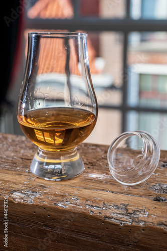 Dram of single malt scotch whisky served in tasting glass with view on old window and houses © barmalini