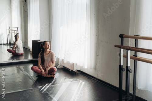 Beautiful happy young woman in pink sportswear resting after successful fitness workout or dance classes sitting on floor. Pleasant fatigue after training. Healthy lifestyle routine. Copyspace 