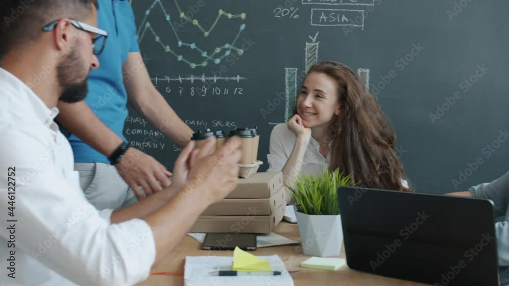 Delivery man in uniform is bringing food and drink to office workers who are clanging coffee cups during lunch break. Workplace and people concept. Delivery man in uniform is bringing food and drink to office workers who are clanging coffee cups during lunch break. Workplace and people concept.