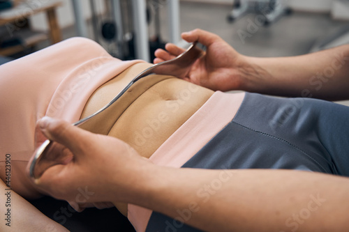 Canvas-taulu Chiropractor massages woman using IASTM tool for scraping muscles in rehab clini