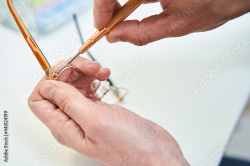 Male optician hands repairing eyeglasses with screwdriver