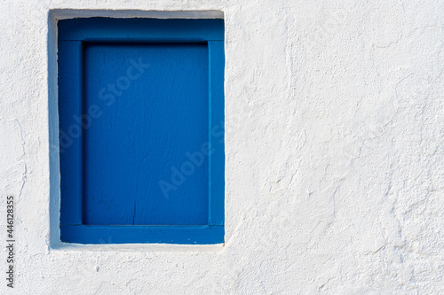 Small blue painted wooden window in a white wall.