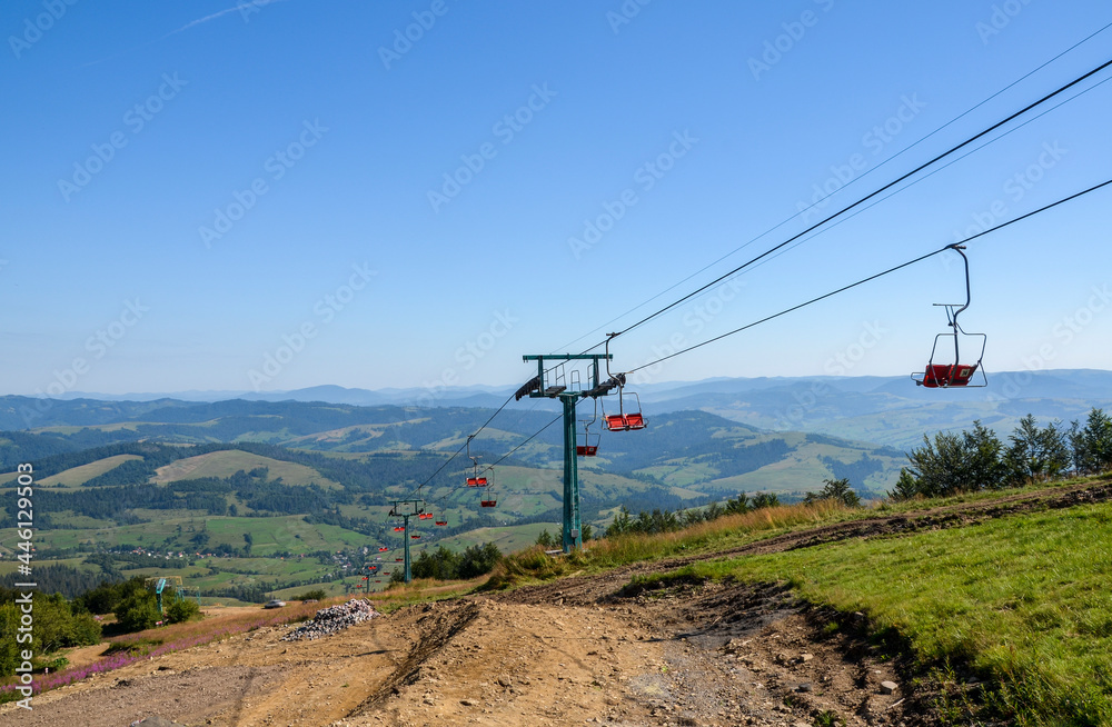 Empty red chairlift in the mountains at ski resort Pylypets during summer clear day. Carpathians, Ukraine