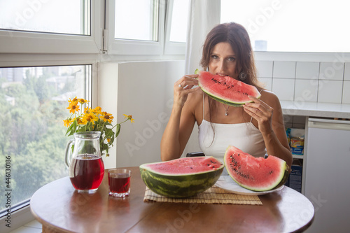 Obraz na plátne Happy European woman holding large slices of watermelon, bright red berry on the table and in the woman's hands