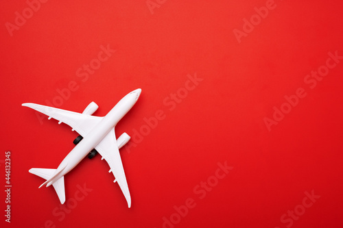 White model of passenger plane on red background, travel concept. Traveling by plane