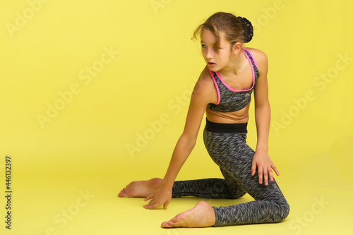 Teen girl posing on the floor in the studio. The concept of style and fashion.