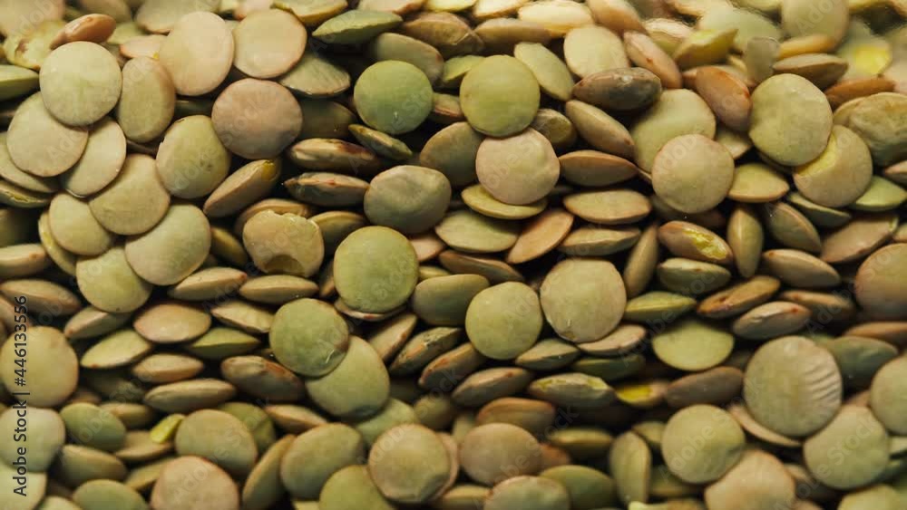 Close-up of falling down green lentils into glass jar on blue background. Shooting of lentil seeds and groats in studio. Macro footage of pouring out the grits. Food cooking video. Close-up of falling down green lentils into glass jar on blue background. Shooting of lentil seeds and groats in studio. Macro footage of pouring out the grits. Food cooking video.