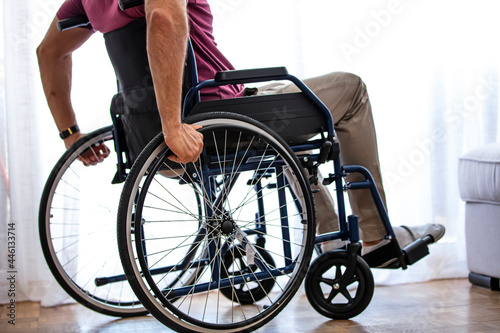 Unrecognizable disabled man sitting in a wheelchair. Man in wheelchair at home or in office. Cropped shot of an unrecognizable senior man sitting in his wheelchair at home