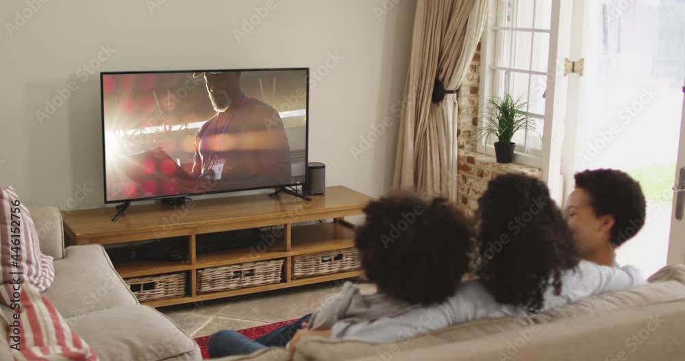 Composite of happy family sitting at home together watching sports event on tv