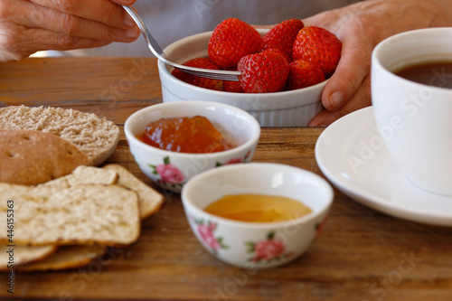 Eating strawberries for breakfast, woman's hands holding a bowl with fruit, healthy eating