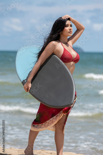 Pretty caucasian woman in sexy bikini posing with surfboard on the ocean seashore get tanned tropic style