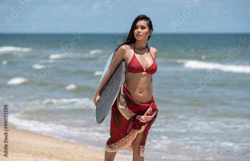 Surfer girl walking with board on the sandy beach