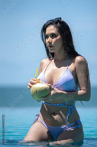 Woman drink coconut in swimming pool