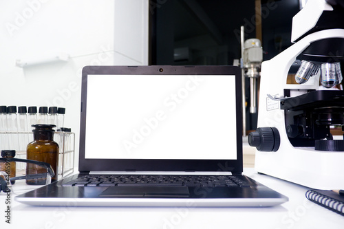 Cropped shot view of white screen labtop and the equipment and science experiments in Laboratory, Chemical substances
for research and analyzing a sample under the microscope in laboratory.