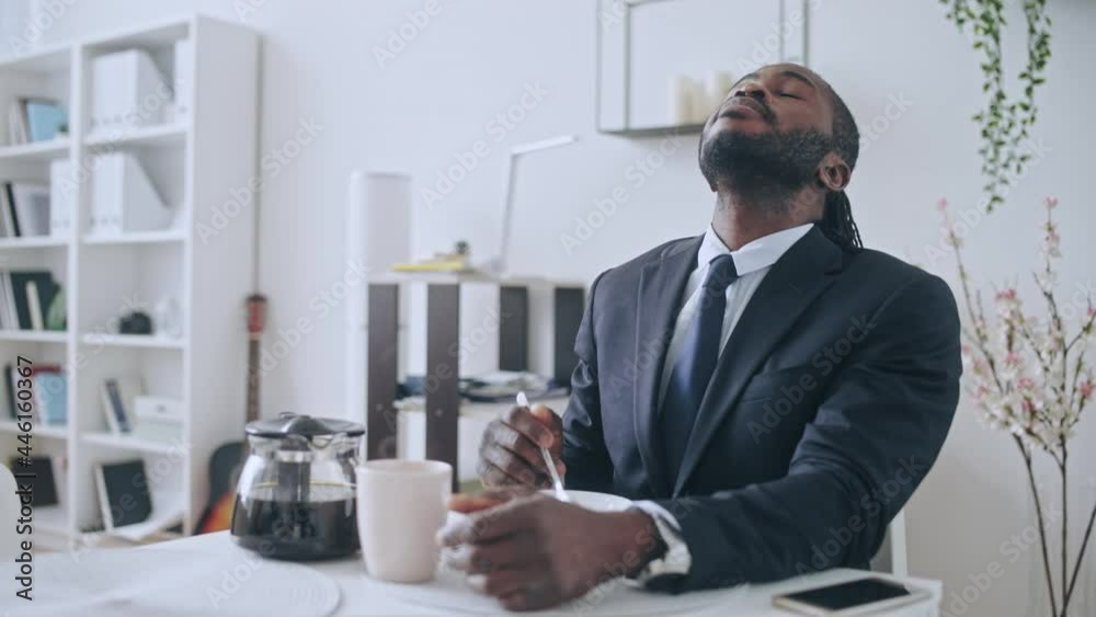 Sleepy African businessman pouring coffee and eating cereal in the morning Sleepy African businessman pouring coffee and eating cereal in the morning