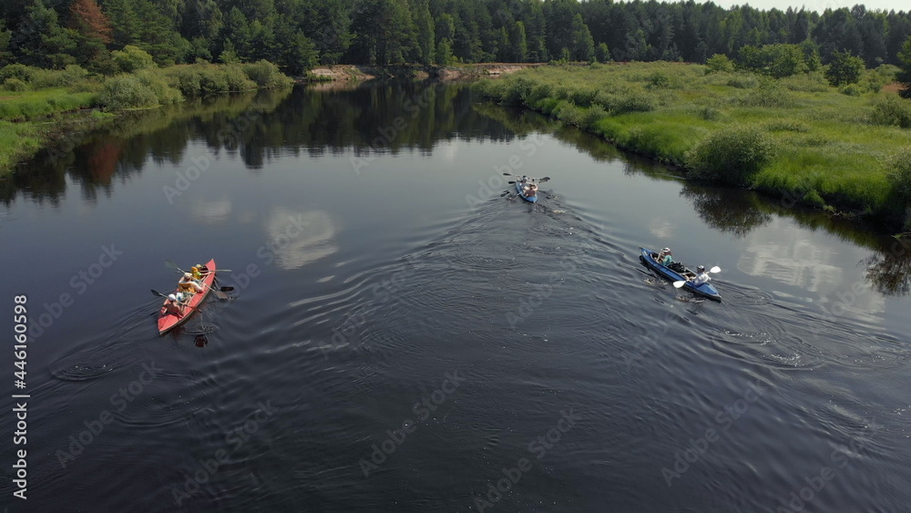 Fototapeta premium Tracking a Boat. Tourist base of kayaks and canoes, summer adventure kayak, rafting to canoe. Kayaking top view. Group of kayaks rowing together. Aerial view from drone.