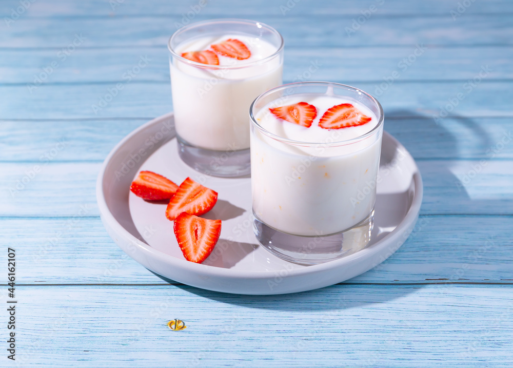 yogurts with strawberries on blue wooden background yogurts with strawberries on blue wooden background