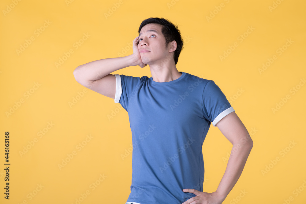 Asian man is bored, isolated on yellow background Asian man is bored, isolated on yellow background