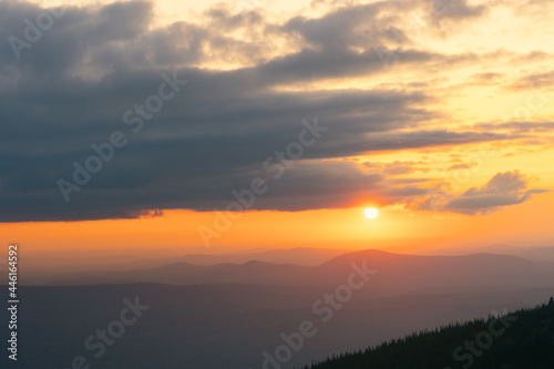 The sun is setting in a mountain valley in summer. panorama of the mountain range at sunset. View from the top.