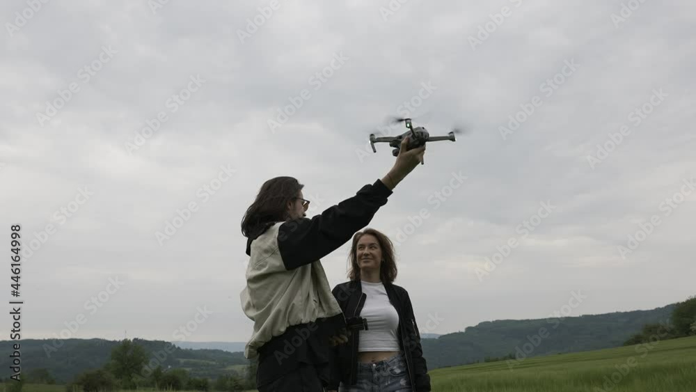 Male and Female Having Fun With Quadcopter Drone. Man Catching Aircraft in Hand After Flight, Slow Motion
