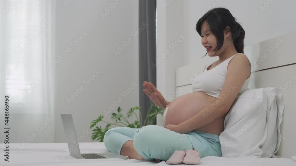 Develop baby communication concept. Pregnant woman taking a video conference with her husband. A pregnant woman is waving to her husband and showing daughter. Develop baby communication concept. Pregnant woman taking a video conference with her husband. A pregnant woman is waving to her husband and showing daughter.