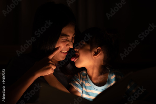asian parent bedtime with kid, mom playing with child, Mother and daughter enjoying on the bed, happy, smiling to each other, family quality time concept . photo
