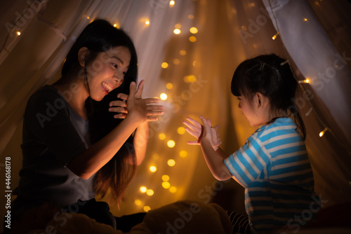 mother and daughter bedtime story reading book and hand shadow art in bed before going to sleep  family concept  quality happy time  dark backgroud