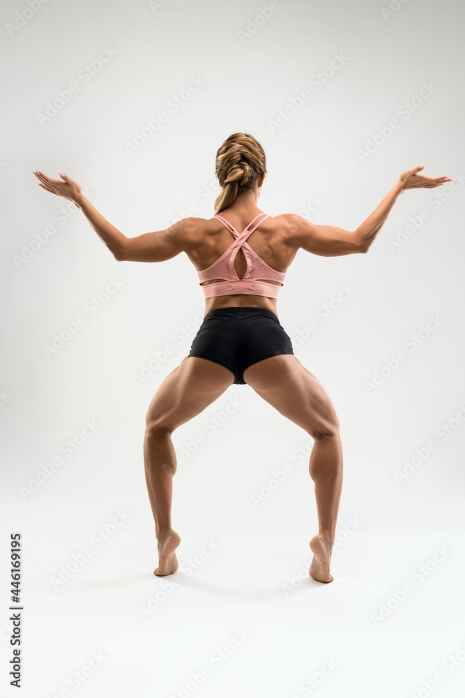 Muscular woman in sports underwear standing in Goddess pose