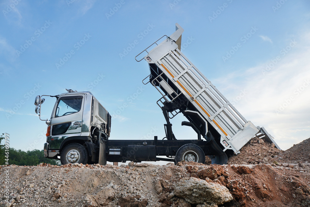 Fototapeta premium The dump truck is pouring soil out of the pickup truck, on construction site. 
