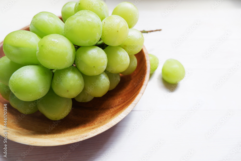 green grape on wooden dish and table background. Fresh organic concept. Shine Muscat, grape, fresh green, natural, natural food, Healthy. green grape on wooden dish and table background. Fresh organic concept. Shine Muscat, grape, fresh green, natural, natural food, Healthy.
