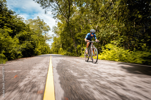 Fototapeta Naklejka Na Ścianę i Meble -  Bike race training, Cyclist speeding mountain bike on road with forest side. Outdoor sport activity fun and enjoy riding. Basic techniques training for safe on trail of athlete.