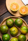 Green tangerine orange fruit in a bamboo basket and cutting on wooden board, Table top view