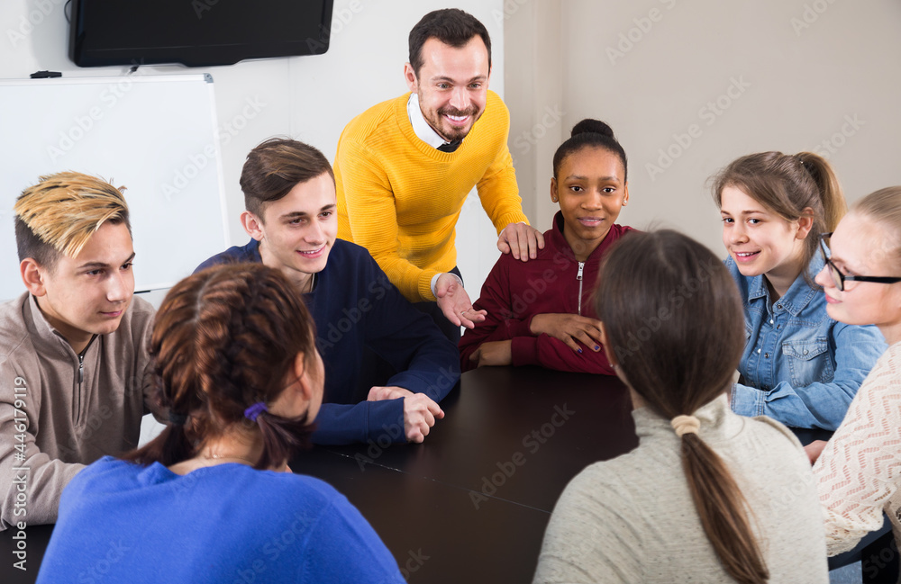 Fototapeta premium cheerful classmates having difficult project to complete during class sits by the table