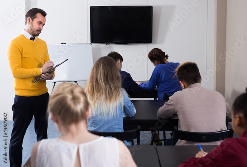 University teacher is monitoring students during revision work in class.