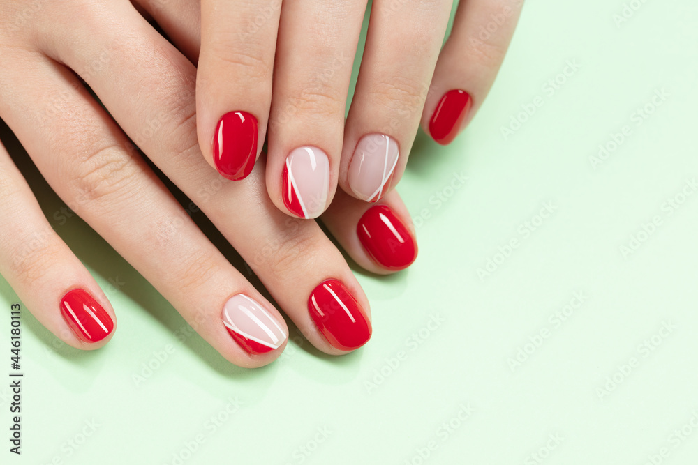 Female hands with new manicure. Hands with pink and red nail polish on a green background. Care for woman hands. Woman in salon receiving manicure by nail beautician. Selective focus Female hands with new manicure. Hands with pink and red nail polish on a green background. Care for woman hands. Woman in salon receiving manicure by nail beautician. Selective focus