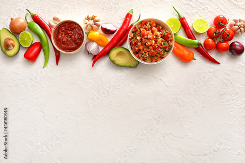 Schilderij op canvas Bowls of tasty salsa sauces with products on white background