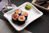 Fresh salmon sushi maki served on white plate with wasabi and soy sauce
