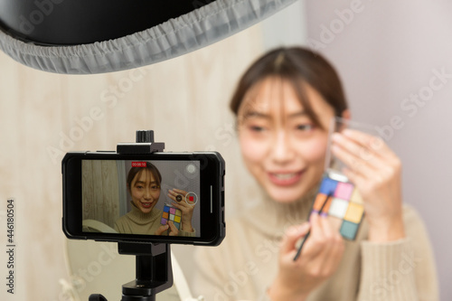 スマートフォンでメイクの動画を撮影する女性