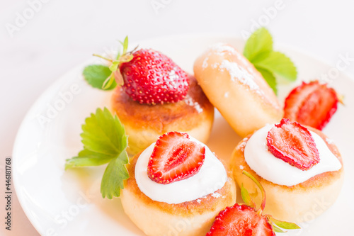 Fototapeta Naklejka Na Ścianę i Meble -  Syrniki, curd or cottage cheese pancakes withstrawberry, powdered suga on a white table