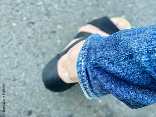 靴擦れで絆創膏を貼ったサンダル履きの足元