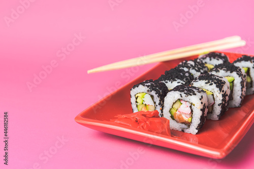 Tasty and fresh sushi set served in a red plate with wooden chopsticks. Close-up, selective focus on sushi. photo