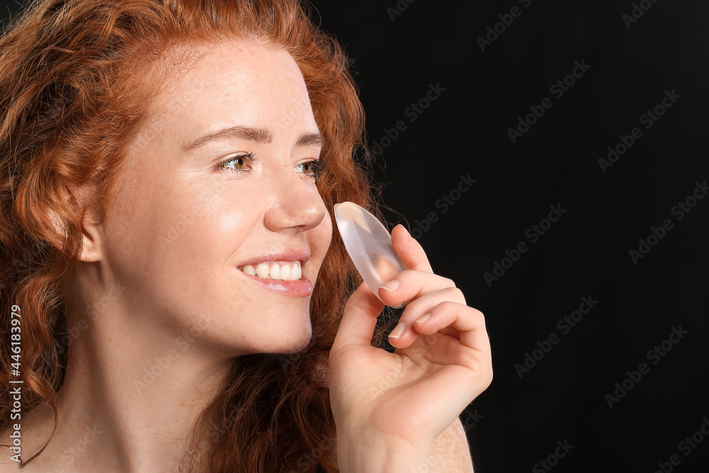 Beautiful young woman with makeup sponge on dark background Beautiful young woman with makeup sponge on dark background