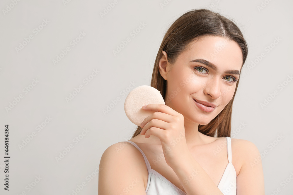 Beautiful young woman with makeup sponge on grey background Beautiful young woman with makeup sponge on grey background