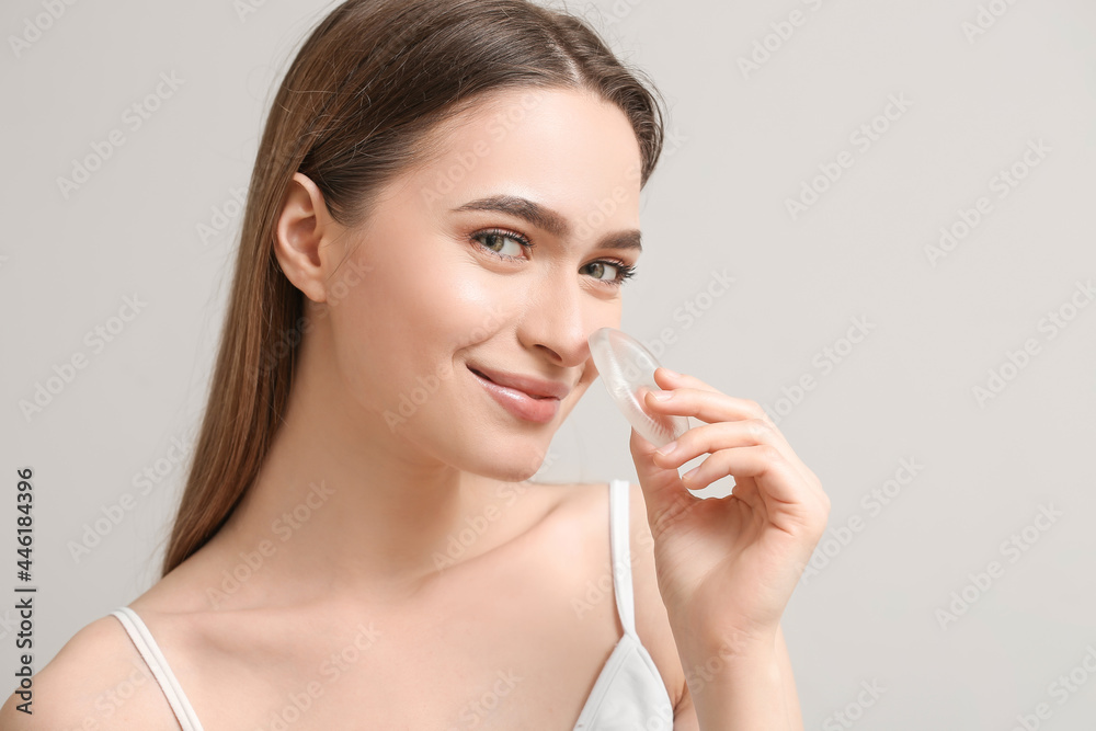 Beautiful young woman with makeup sponge on grey background Beautiful young woman with makeup sponge on grey background