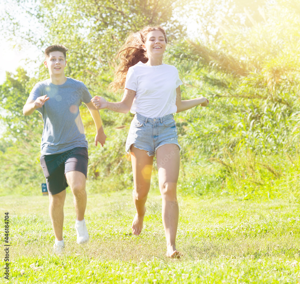 Obraz premium Young man and girl are running on the grass together